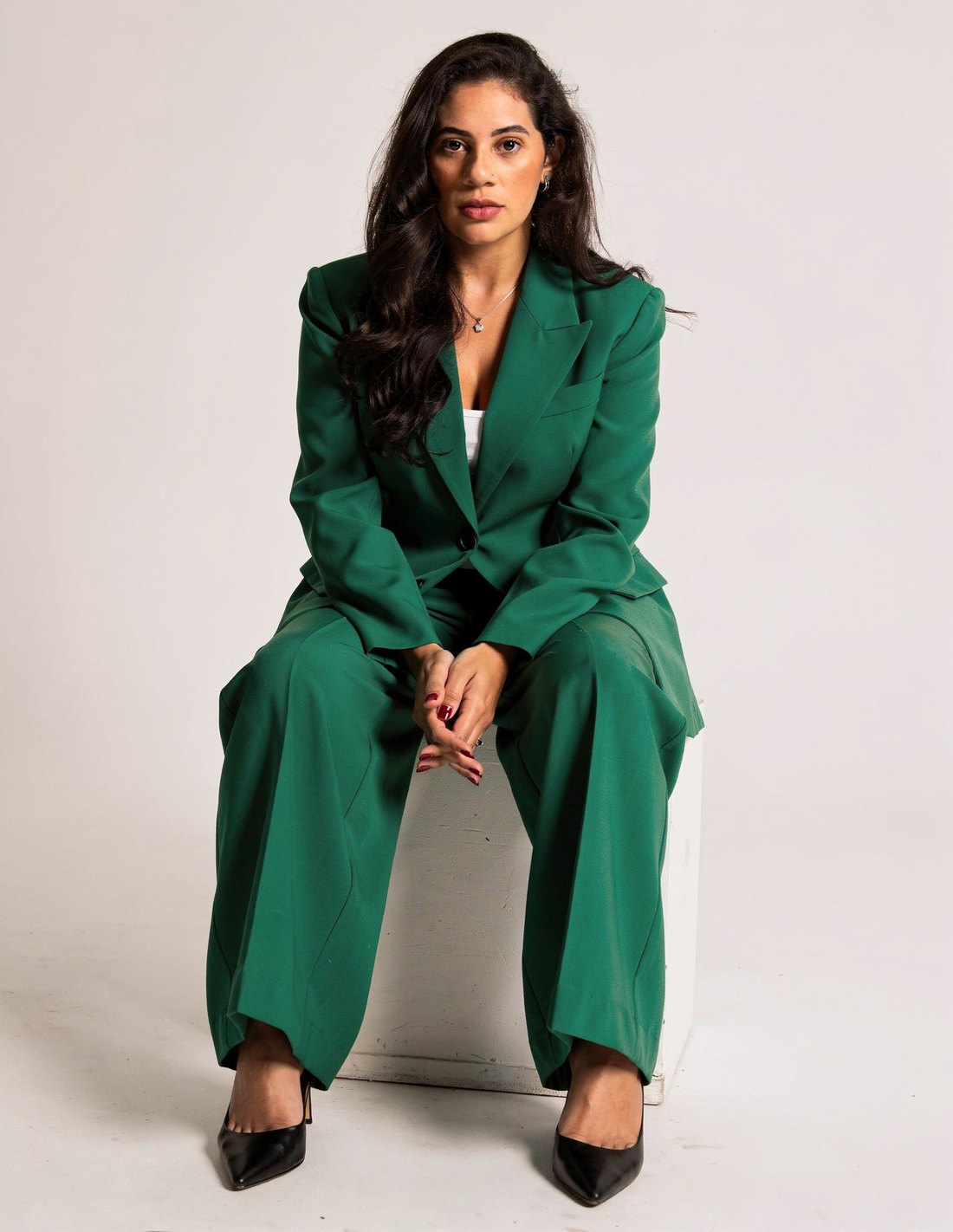 Yasmin Reis em terno verde, sentada
